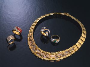 Gold rings and necklace with jewels, high angle view, black background