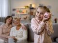 Daughter holding piggybank, mother and granny behind, teaching to save money