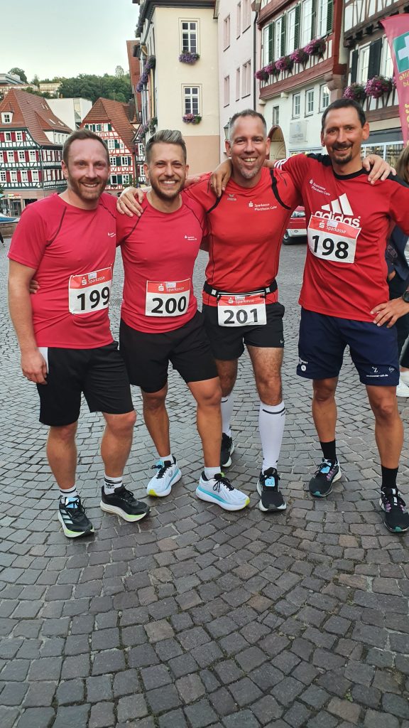 Gruppe von jungen Läufern. Altstadt im Hintergund. Alle im roten Shirt uns freundlichen Gesichtsausdruck.