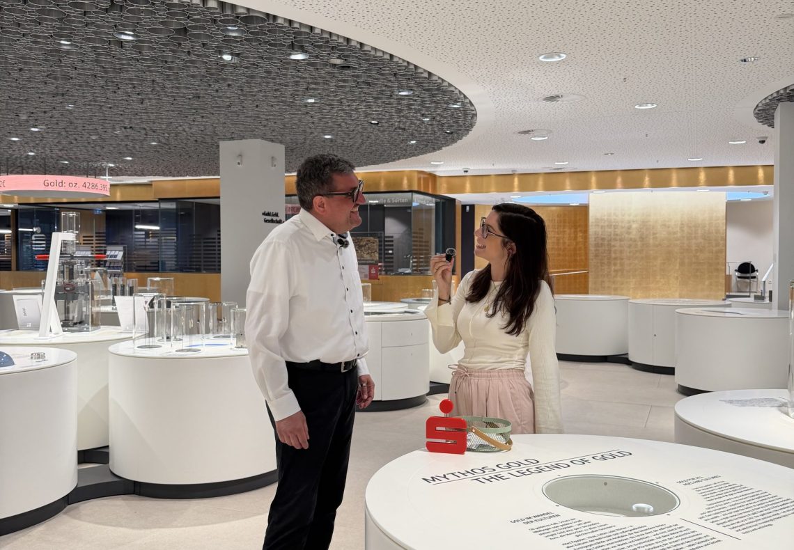 Boris Berenz im Interview mit Kollegin Natalie Ehrismann. Im Hintergund die Ausstellung Gold Geld Gessellschaft und der Sortenschalter der Sparkasse PF CW